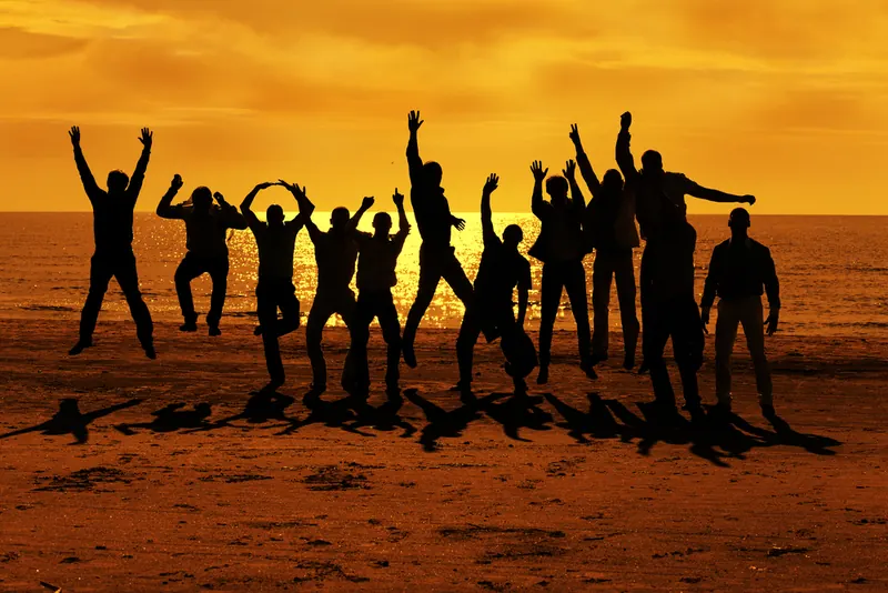 Silhouettes d’un groupe d’amis sautant de joie au coucher du soleil pour un EVG à Cannes