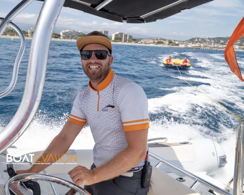 Pilote diplômé à la barre du bateau tractant une bouée dans la baie de Cannes